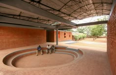 three people are sitting in the middle of a circular area with brick walls and roof