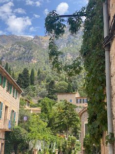 an alley way with stone buildings and greenery on both sides, surrounded by mountains