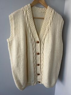 Gorgeous handknit sweater vest with classic button down design. Made from a soft yard (wool/acrylic blend) in a neutral ivory color makes it versatile and perfect for layering over your favorite tops or dresses.  Estimated Size (Not Tag): Large Recommended for sizes M-XL depending on desired fit.  Flat Lay Measurements: Chest: 25" Waist: 24" Length: 27" Materials (no tag): Appears to be a wool blend. 2/5 itchy Excellent condition, no visible flaws. Note:  Vintage items may have subtle imperfecti Button Up Sweater Vest, Button Up Sweater, Hand Knitted Sweaters, Vest Outfits, Knit Vest, Ivory Color, Sweater Vest, Womens Vest, Flat Lay