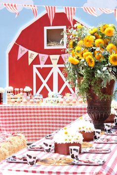 a red and white checkered table cloth with sunflowers in a vase on it