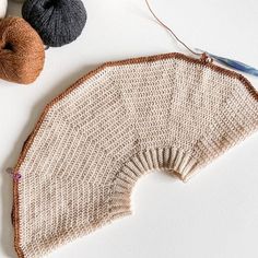 two skeins of yarn next to a knitted fan on a table top