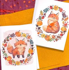 two cards with watercolor drawings of foxes and pumpkins on them, sitting next to each other