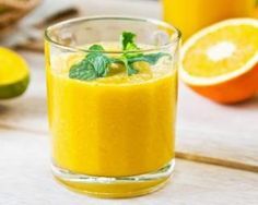 a glass filled with orange juice next to some fruit