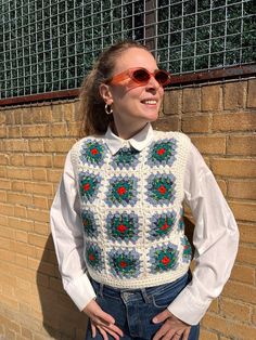 a woman standing in front of a brick wall with her hands on her hips wearing sunglasses