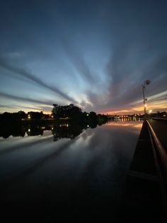 the sun is setting over a body of water with clouds in the sky above it