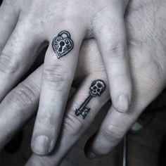 two people with tattoos on their fingers and one has a heart shaped key tattoo on the middle finger