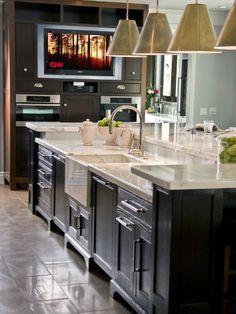 a large kitchen with an island in the middle and two pendant lights hanging from the ceiling