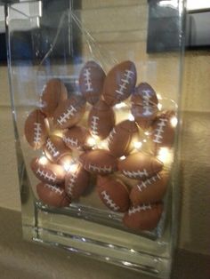 a clear container filled with chocolate covered footballs on top of a countertop next to a window