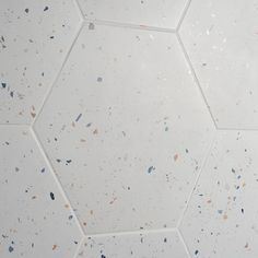 a white tiled floor with small pieces of blue and brown speckles on it