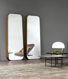 two large mirrors sitting next to each other on top of a wall above a table