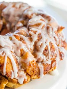 two cinnamon rolls covered in icing on a white plate