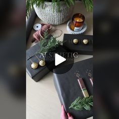 a table topped with books and plants next to a vase filled with pine cones on top of