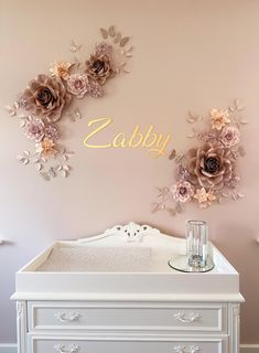 a baby crib in front of a wall with flowers and the name zabby on it