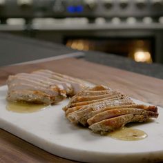 two pieces of meat sitting on top of a cutting board next to some sauces