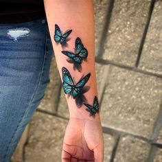 a woman's arm with three blue butterflies on her left wrist and one in the middle