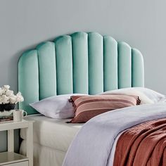 a bed with a blue headboard and pillows on it's sides, next to a night stand