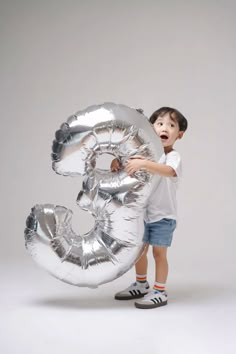 a young boy is holding the number three balloon