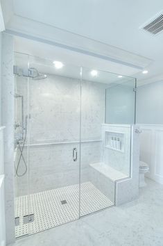 a bathroom with a walk in shower next to a white toilet and tiled flooring