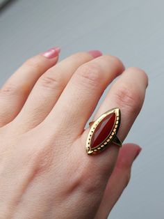 Lovely Red Carnelian navette ring in 14k gold. The Carnelian is faceted and bezel set in a yellow gold mount. Nice ornament on the gold mount and elegant shoulders. Details: The ring is vintage and made of 14k gold.  Condition: It is in excellent vintage condition. I don't see any wear to the Carnelian and the shank is solid all around, equal thickness no sign of thinning.  Measurements: The ring is a US size 7. The visible part of the Carnelian from the front of the ring measures 20 x 6.5mm. Please note that I don't accept returns, therefore I describe the items with as much details as possible. Please inspect all photos before purchase, and I would also recommend to try to get a sense of the size, for example measuring a ring that you own and compare the measurements. Please also do not Vintage Bezel Ring, Navette Ring, Red Carnelian, Carnelian Ring, Bezel Ring, Bezel Setting, Rings Statement, Switzerland, Statement Rings