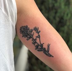 a black and white photo of a flower tattoo on the left upper half of the arm