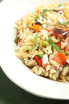 a white bowl filled with rice and vegetables on top of a green table cloth next to a fork