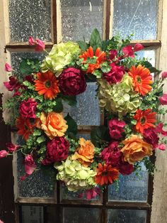 a wreath made out of flowers sitting in front of a window