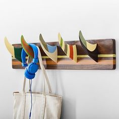 a bag hanging on a wall next to a coat rack with headphones and earbuds