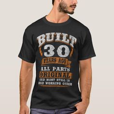 a man wearing a black t - shirt with the words built forty years ago, all parts