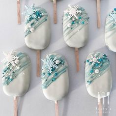 there are many snowflakes on the pops with blue and white icing