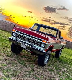 an old ford pickup truck parked in a field with the sun setting on it's horizon