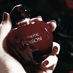 a woman holding a bottle of perfume in her hand with the words hypnotic poison on it