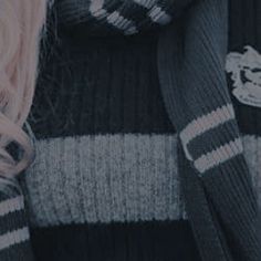 a woman with pink hair is sitting on a couch wearing a black and white striped sweater