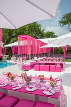 an outdoor dining area with pink and white tables, chairs, and umbrellas over the pool