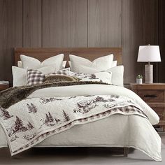 a bed with white and brown comforters in a bedroom next to a night stand