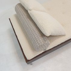 two pillows sitting on top of a white rug next to a pillow that looks like a couch