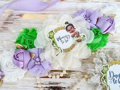 some purple and green flowers are sitting on a white wooden surface with a tag that says happy birthday to you