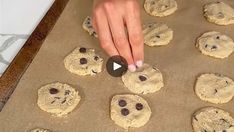 someone placing chocolate chip cookies on a cookie sheet to make them look like they have been baked