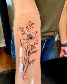 a woman's arm with a flower tattoo on the left side of her arm