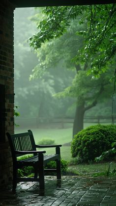 a wooden bench sitting on top of a brick walkway next to a lush green park