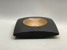 a wooden bowl sitting on top of a black piece of paper next to a white wall