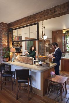 a man and woman standing in a kitchen next to a table with food on it