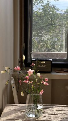 a vase filled with flowers sitting on top of a wooden table next to a window