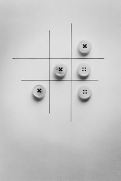 four buttons are arranged in the middle of a cross - stitched pattern on a white surface