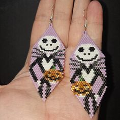 a pair of beaded earrings that look like the character jack skellingy cat