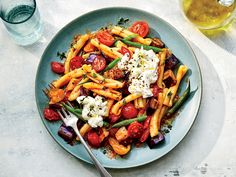 a plate of pasta with tomatoes, green beans and fettuccine on it