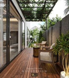 a wooden deck with chairs and tables under a pergolated roof next to a potted plant