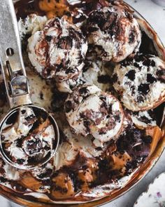 a bowl filled with ice cream and chocolate covered muffins next to a spoon