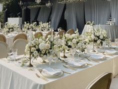 the table is set with white flowers and place settings for an elegant dinnereon party