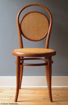 a wooden chair sitting on top of a hard wood floor next to a gray wall