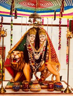 a statue of two women and a lion in front of a colorful tent with lights